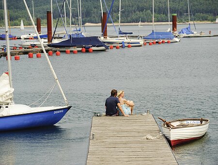 Auf dem Steg des Ramsbergers Segelhafens am Brombachsee genießen zwei Verliebte die wunderschöne Aussicht auf den Brombachsee und die Segelschiffe.