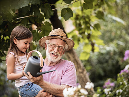 Little girl helping her grandpa watering plants