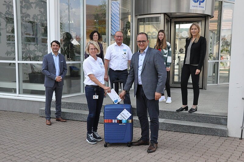 Altmühlfranken 2030 Eine Gruppe an Menschen die vor einer Eingangstür stehen. Vor Ihnen steht ein blauer Reisekoffer.