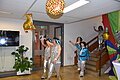 Damen in silber-blauen Kostümen laufen in das Foyer ein und winken dabei. Von der Decke hängen bunte Luftballons.