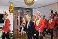 Ein Prinzenpaar mit Hofgefolge läuft in das Foyer ein. Sie tragen rote Jackets und bunte Hüte.