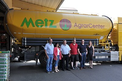 Unternehmensbesuch - Metz Agrar Center GmbH Landrat Gerhard Wägemann und Sabine Unterlandstaettner von der Wirtschaftsförderung mit den Vertretern der Metz Agrar Center GmbH auf dem Betriebsgelände vor einem Fahrzeug des Unternehmens.