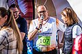 Landrat Manuel Westphal trägt ein buntes Lauftrikot und spricht in ein Mikrofon.