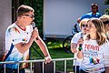 Zwei Moderatoren mit weißen Trikots sprechen in ein Mikrofon.