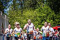 Läuferinnen und Läufer in weiß/bunten Trikots laufen gemeinsam ins Ziel ein. Vor Ihnen liegt ein blauer Teppich am Boden.