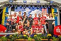 Die Mannschaft Arriba Göppersdorf mit roten Trikots kniet und steht auf der Bühne und hält den goldenen Wanderpokal in der Hand.