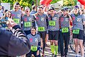 Ein Team mit grauen Trikots und grüner Startnummer steht im Halbkreis, umarmt sich und lässt sich fotografieren.