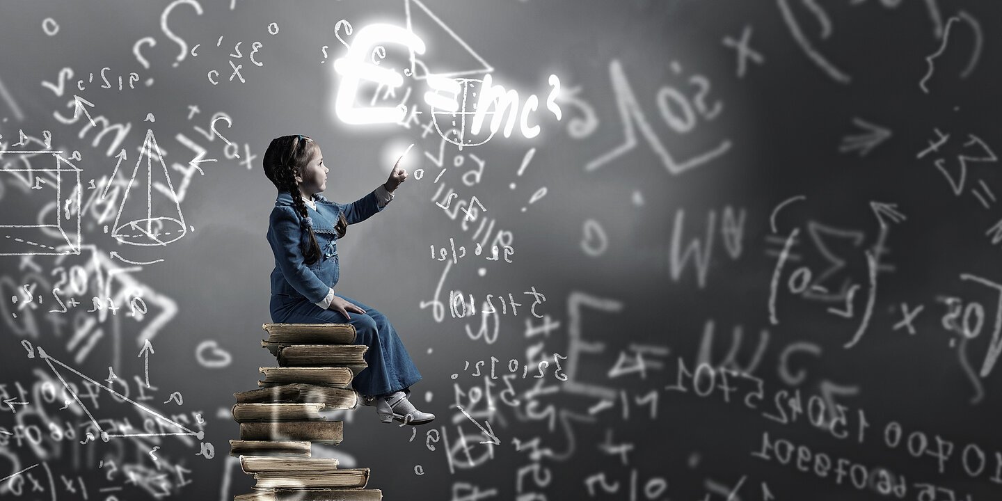 Little girl sitting on stack of books and touching science formula
