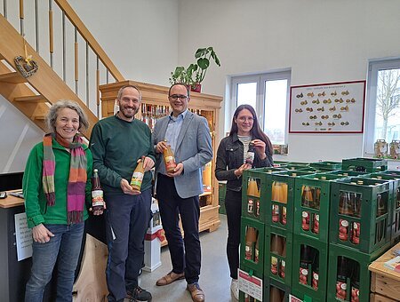 Es sind vier Personen zu sehen, welche die Produkte der Mosterei in den Händen halten und für ein Gruppenbild in die Kamera schauen.
