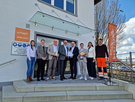 Ein Gruppe von Männern und Frauen präsentiert die Urkunde des Umwelt- und Klimapakt Bayern und blickt dabei für ein Gruppenbild in die Kamera.