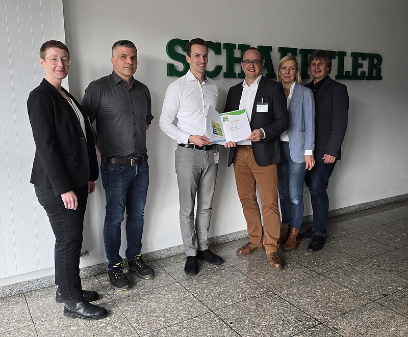 Mehrere Personen blicken in die Kamera und präsentieren die Urkunde zum Klimapakt Bayern.