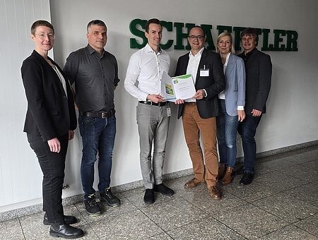 Mehrere Personen blicken in die Kamera und präsentieren die Urkunde zum Klimapakt Bayern.