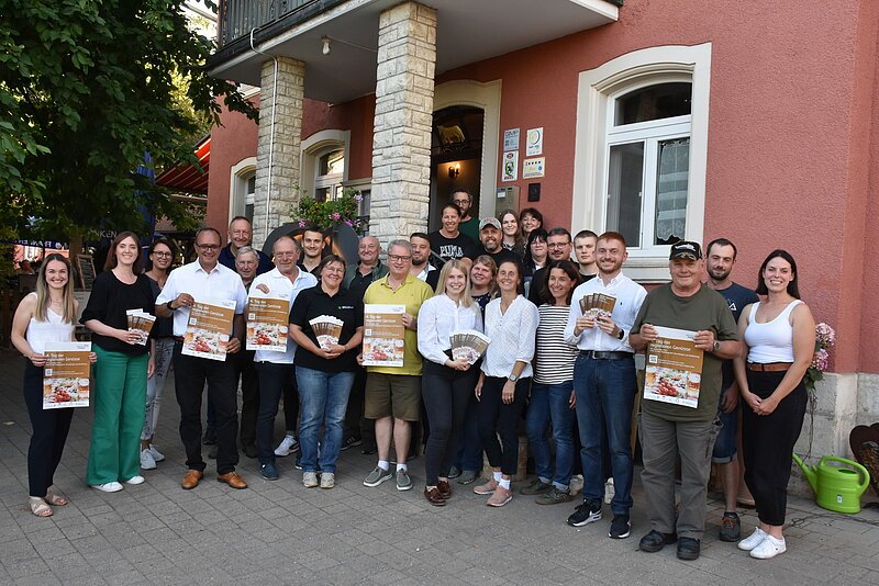 Auf dem Gruppenfoto vor einem rötlichen Haus sind die teilnehmenden Betriebe und Projektpartner vom Tag der regionalen Genüsse abgebildet