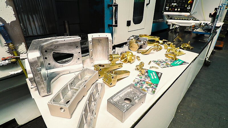 Auf dem Bild sind Produkte von Krause Kokillenguss zu sehen, sprich in Formen gegossene Metallstücke. Diese liegen auf einem Tisch.
