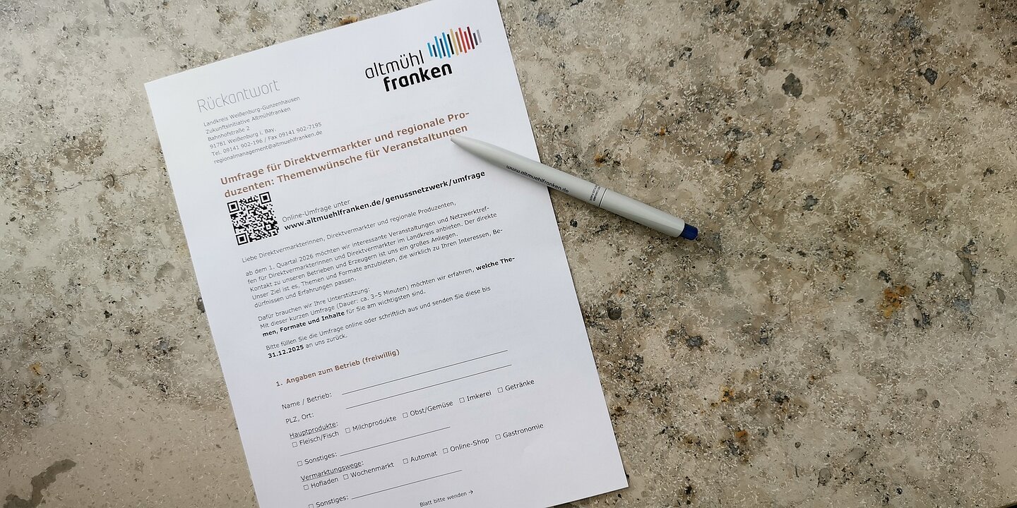 Ein Blatt Papier auf einem Marmortisch, auf dem ein Kugelschreiber liegt. Es handelt sich um einen Umfragebogen.