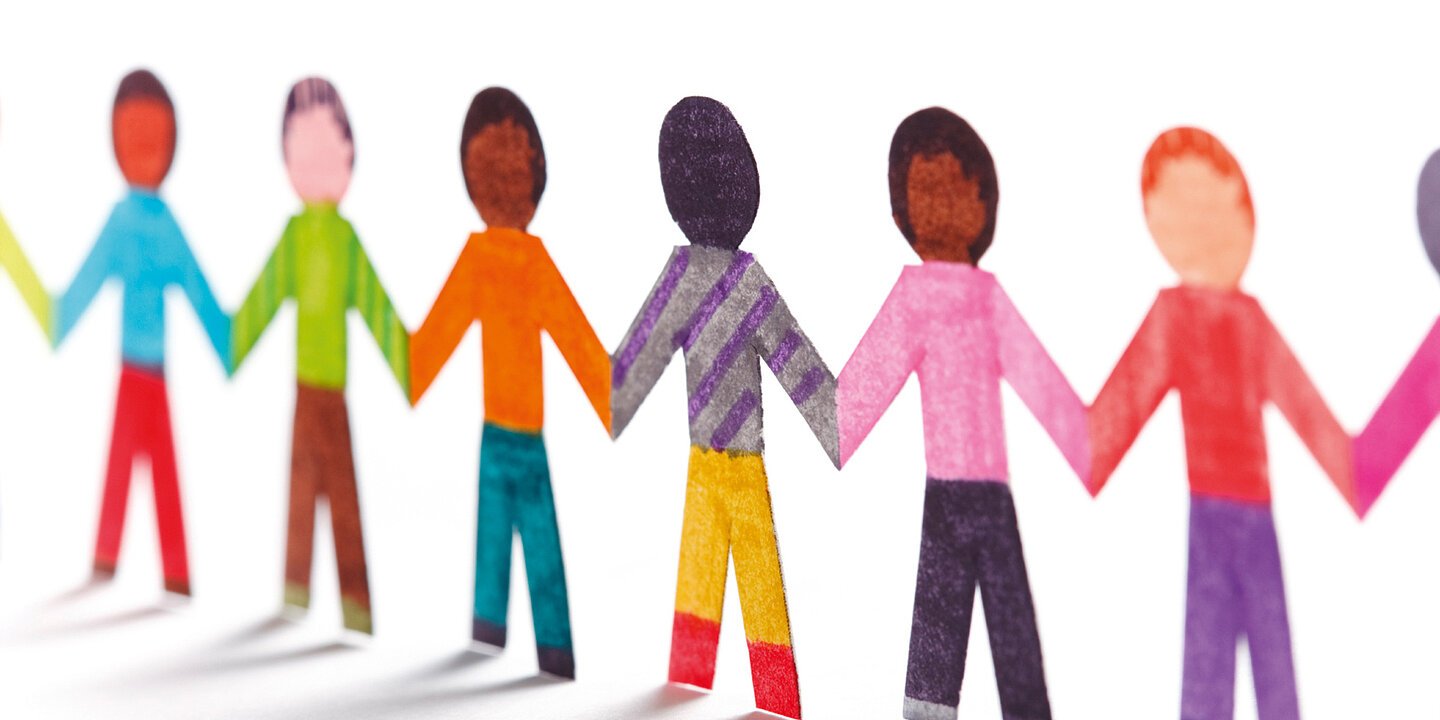 Bunte Piktogramm-Menschen halten sich an den Händen. Sie bilden symbolisch eine Menschenkette als Zeichen der Zusammengehörigkeit, für Vielfalt und gegen Rassismus