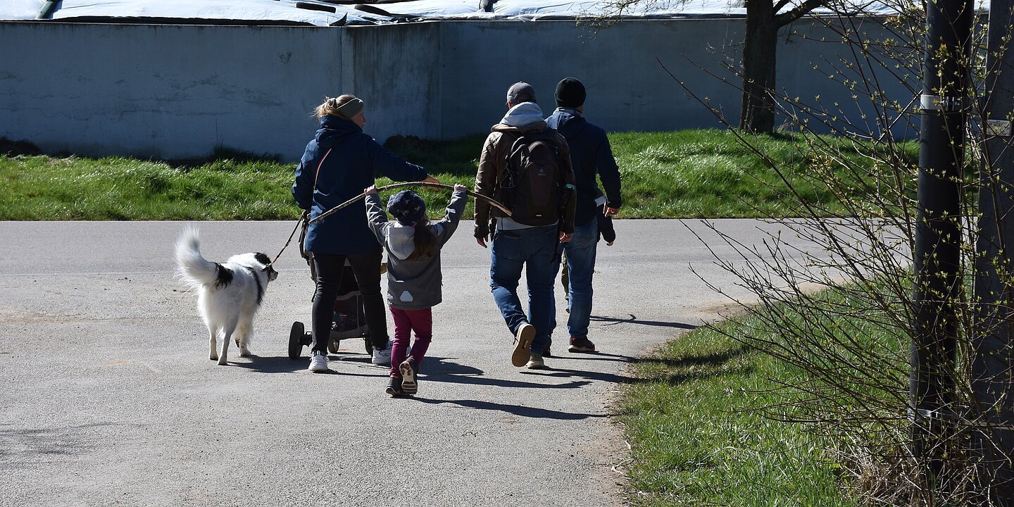 Eine Familie läuft mit ihrem Hund entlang einer ausgeschilderten Route.