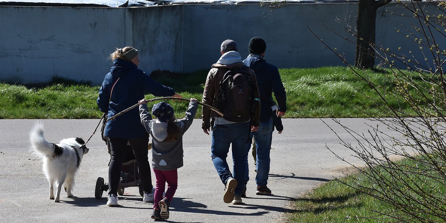 Eine Familie läuft mit ihrem Hund entlang einer ausgeschilderten Route.