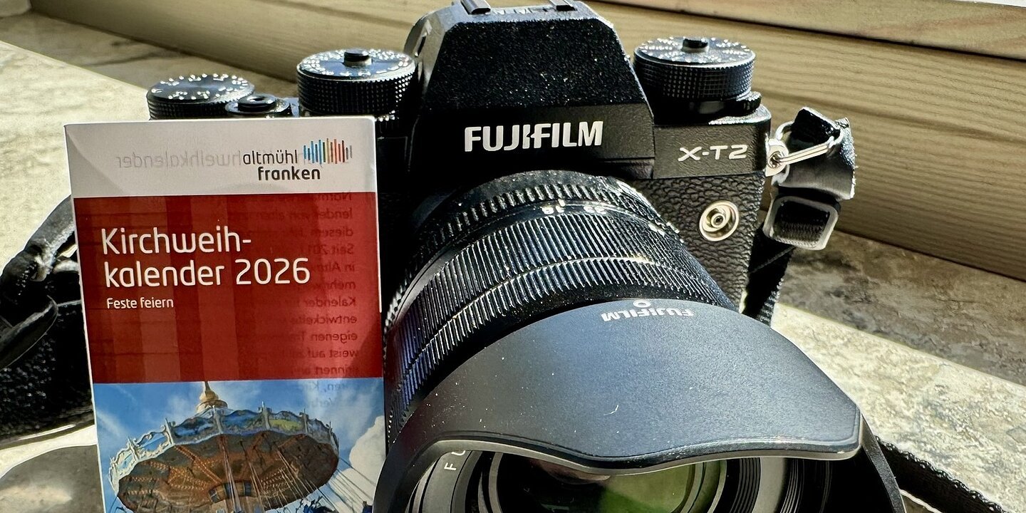 Eine Kamera liegt mit dem Kirchweihkalender zusammen auf einer sonnigen Fensterbank